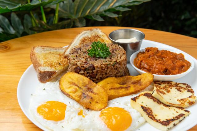 Desayuno con gallo pinto, dos huevos fritos, plátano maduro, queso asado, pan tostado y salsa de tomate.